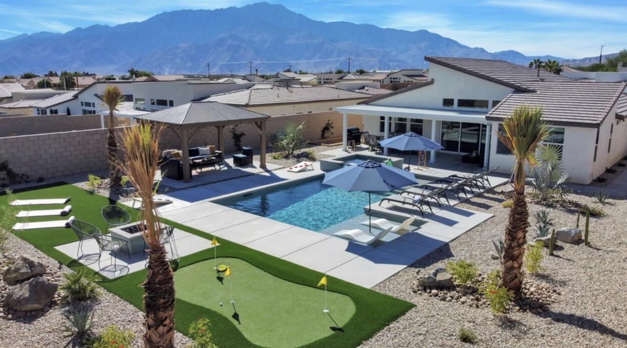 Backyard with a swimming pool, putting green, palms and mountain views